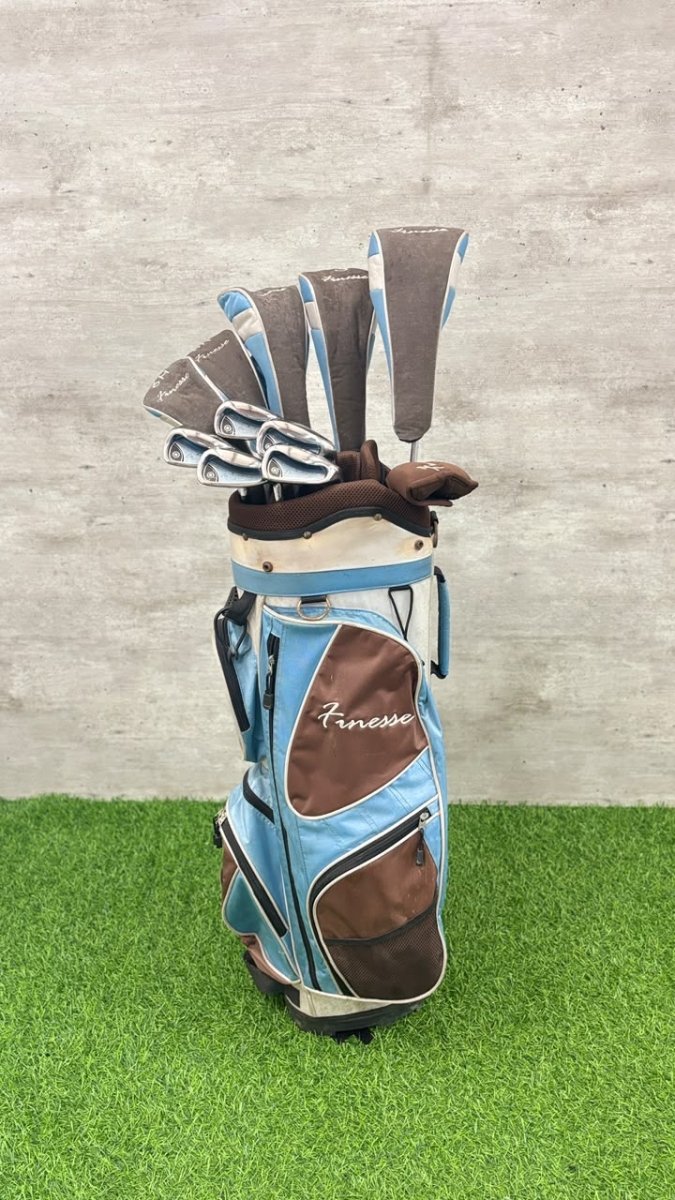 Golf bag with clubs on a grassy surface against a gray wall
