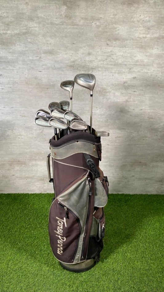 Golf bag with golf clubs on a grassy surface with a concrete wall background