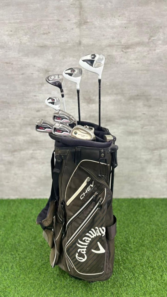Callaway golf clubs in a bag on grass with a gray background