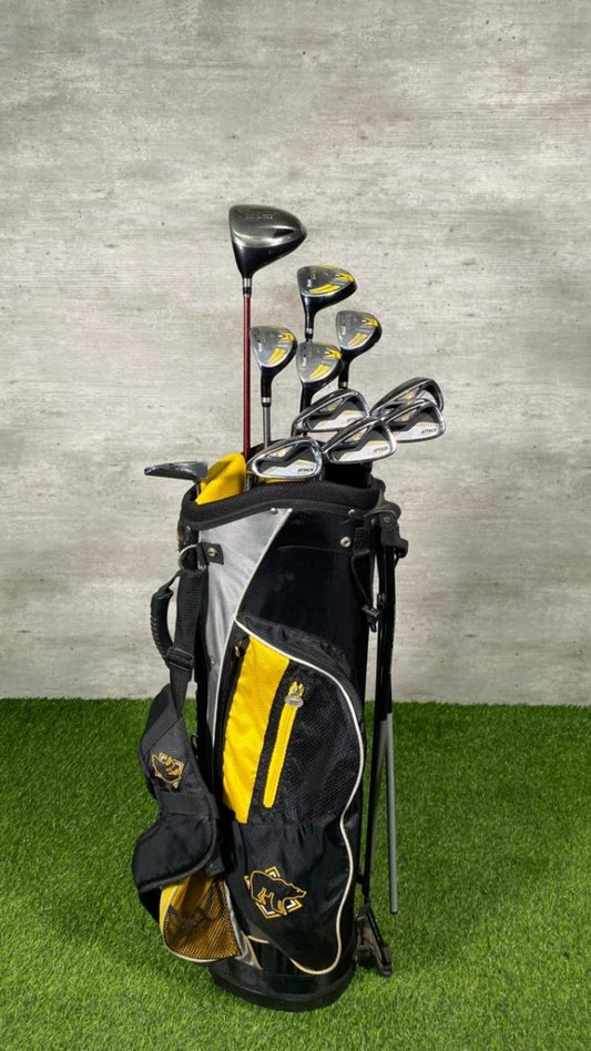 Set of golf clubs in a black and yellow bag on a green surface with a gray background