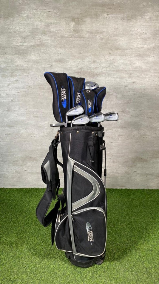 Golf club set with black and gray bag on grass against a concrete wall