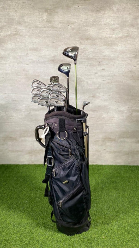 Golf bag with clubs on a grassy surface against a textured wall