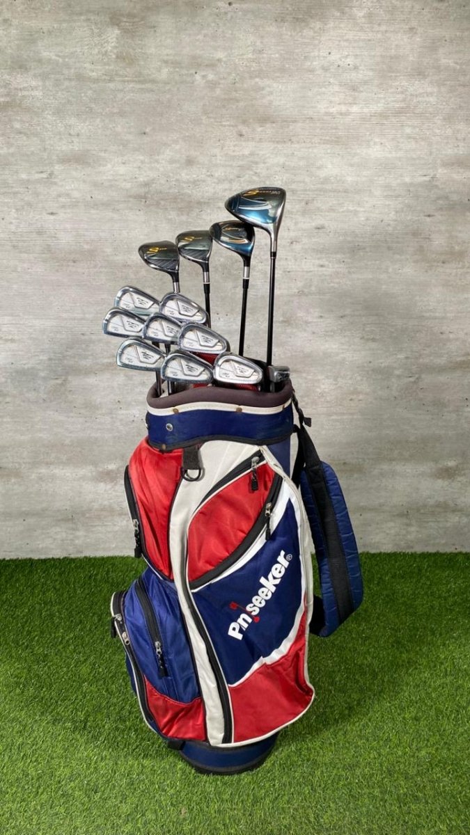 Golf clubs in a red and blue bag on a green surface with a gray background