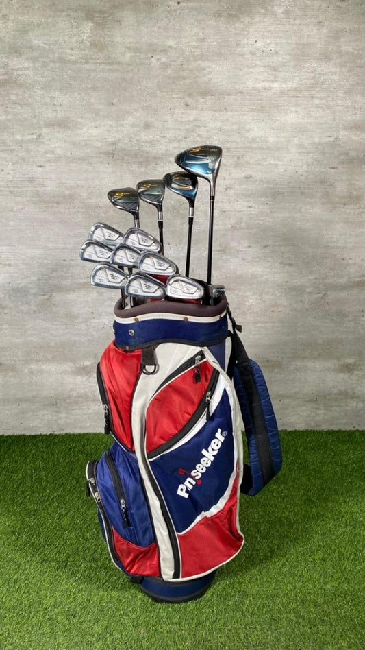 Golf clubs in a red and blue bag on a green surface with a gray background