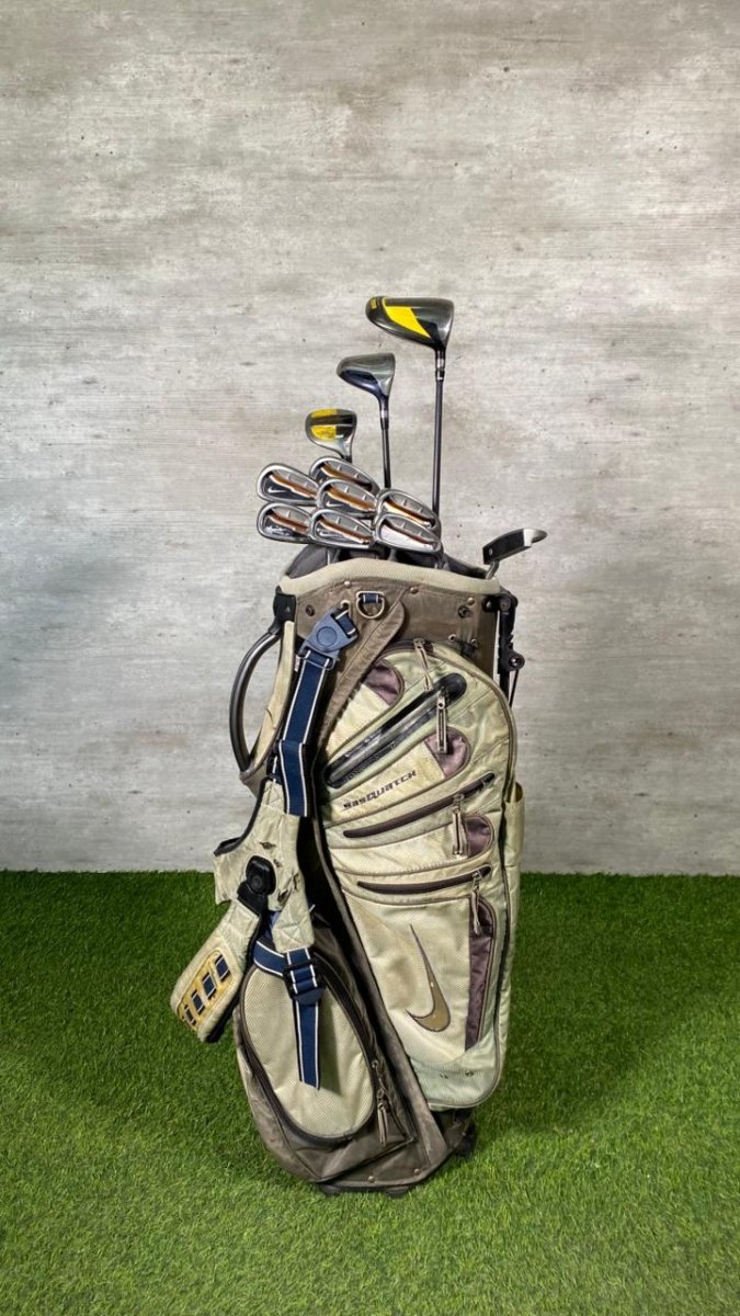 Golf bag with clubs on a grassy surface against a textured wall