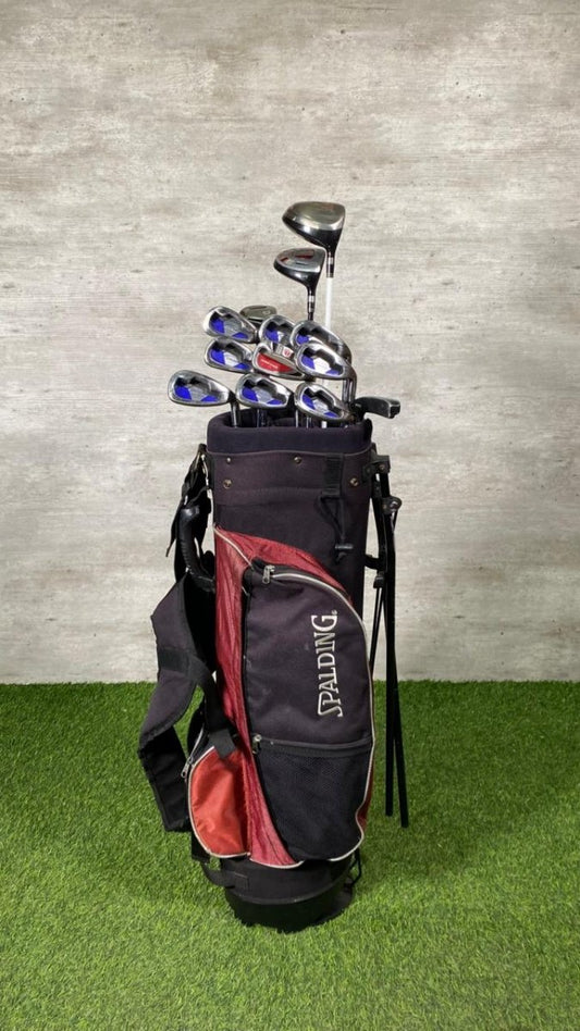 Golf bag with golf clubs on a grassy surface with a gray wall background
