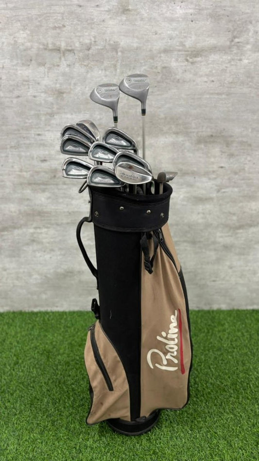Golf clubs in a Proline bag on a grassy surface with a concrete wall background