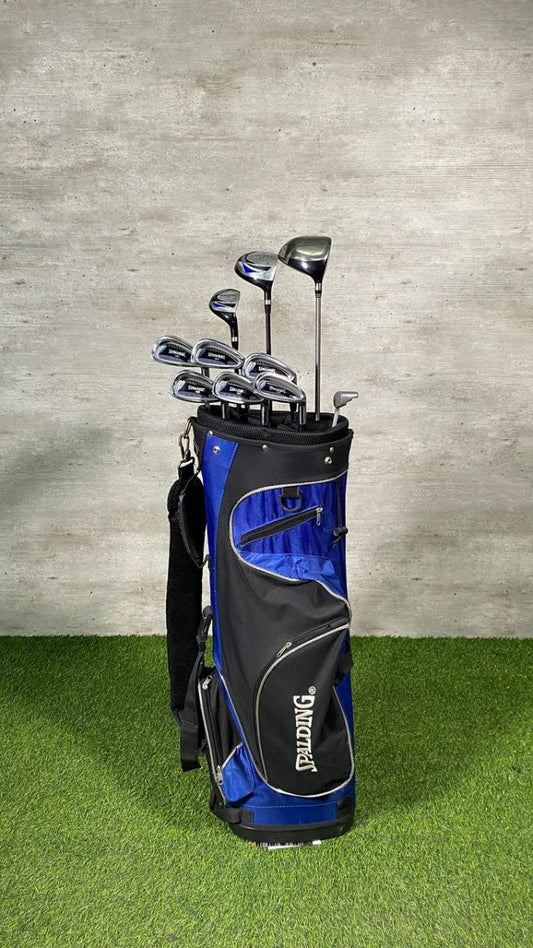 Golf club set in a black and blue bag on a grassy surface with a concrete wall background