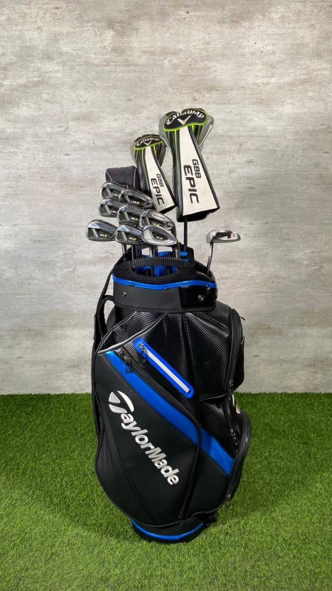 Golf clubs in a TaylorMade bag on a grass and concrete background