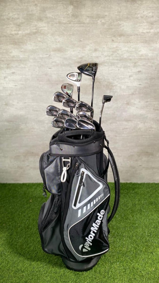 Golf bag with golf clubs on a green surface and gray background