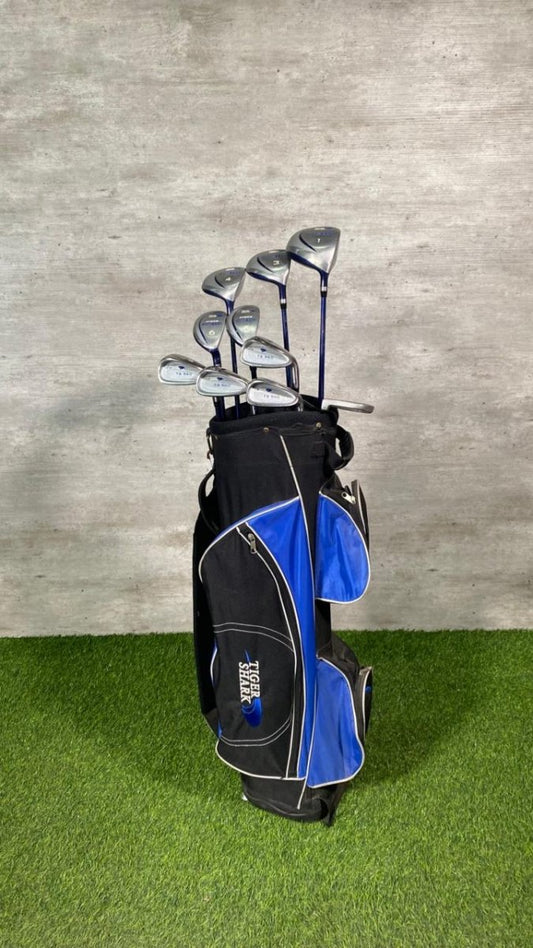Golf clubs in a black and blue bag on a green surface with a gray background