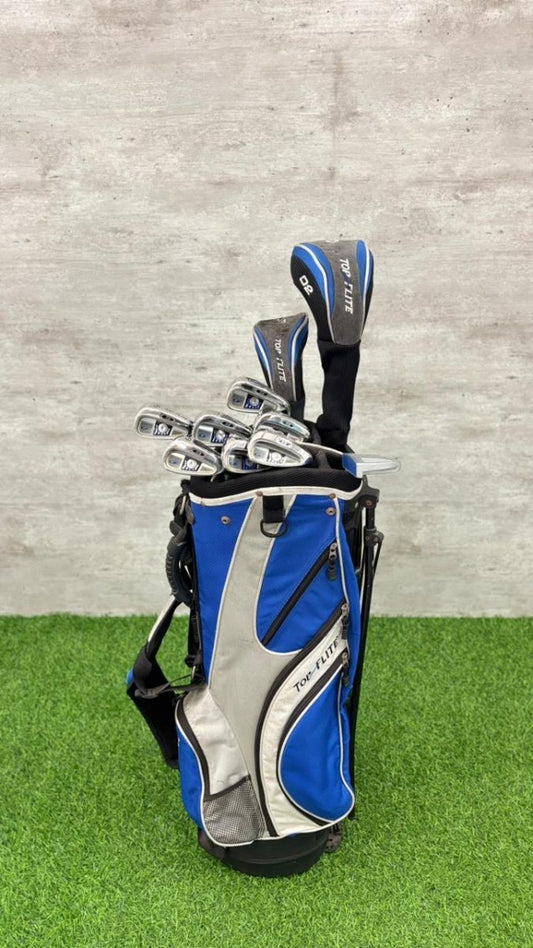 Golf clubs in a blue and gray bag on green grass with a gray wall background