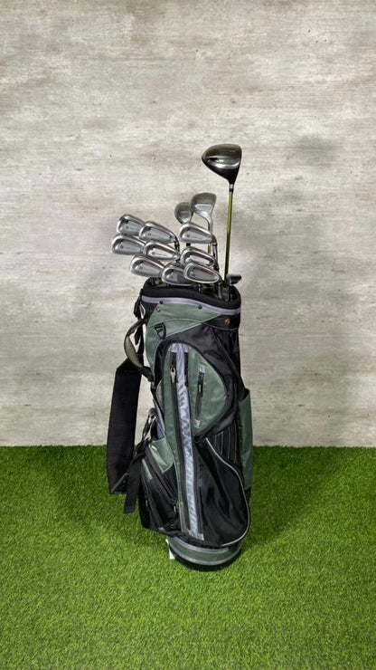 Golf clubs in a black bag on a green surface with a gray textured wall background