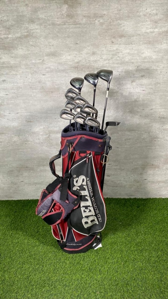 Golf clubs in a black and red bag on a green surface with a gray background