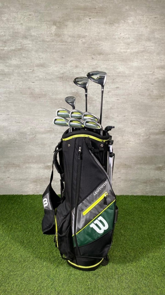 Golf bag with golf clubs against a gray wall