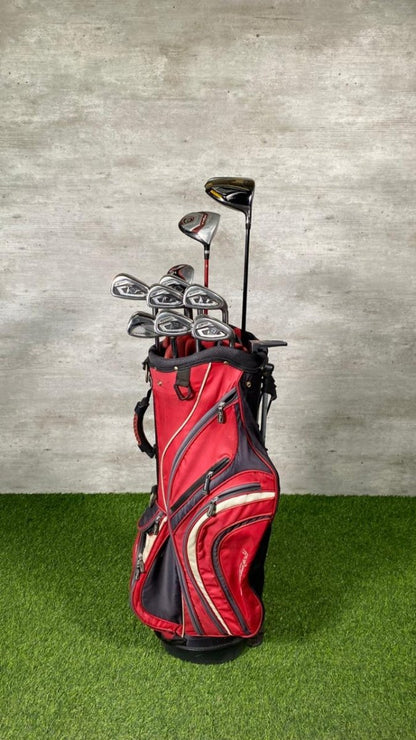 Red golf bag with golf clubs on a grassy surface and concrete wall background
