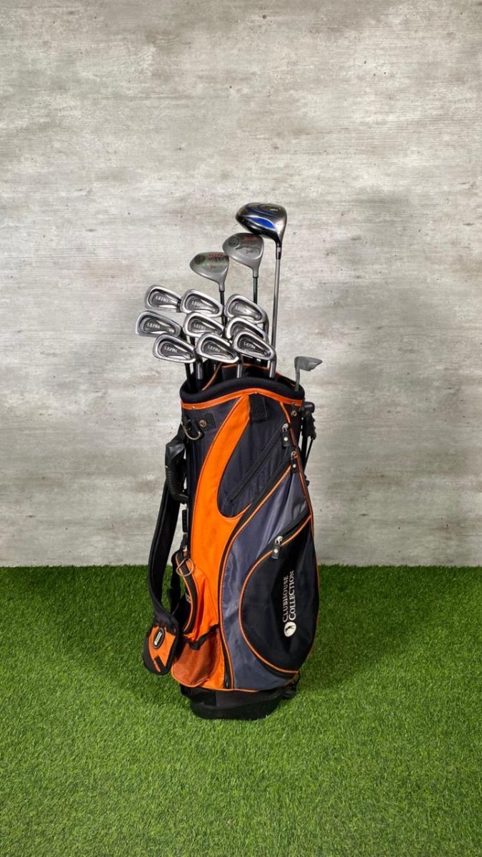 Golf clubs in an orange and black bag on a green surface with a gray textured wall background